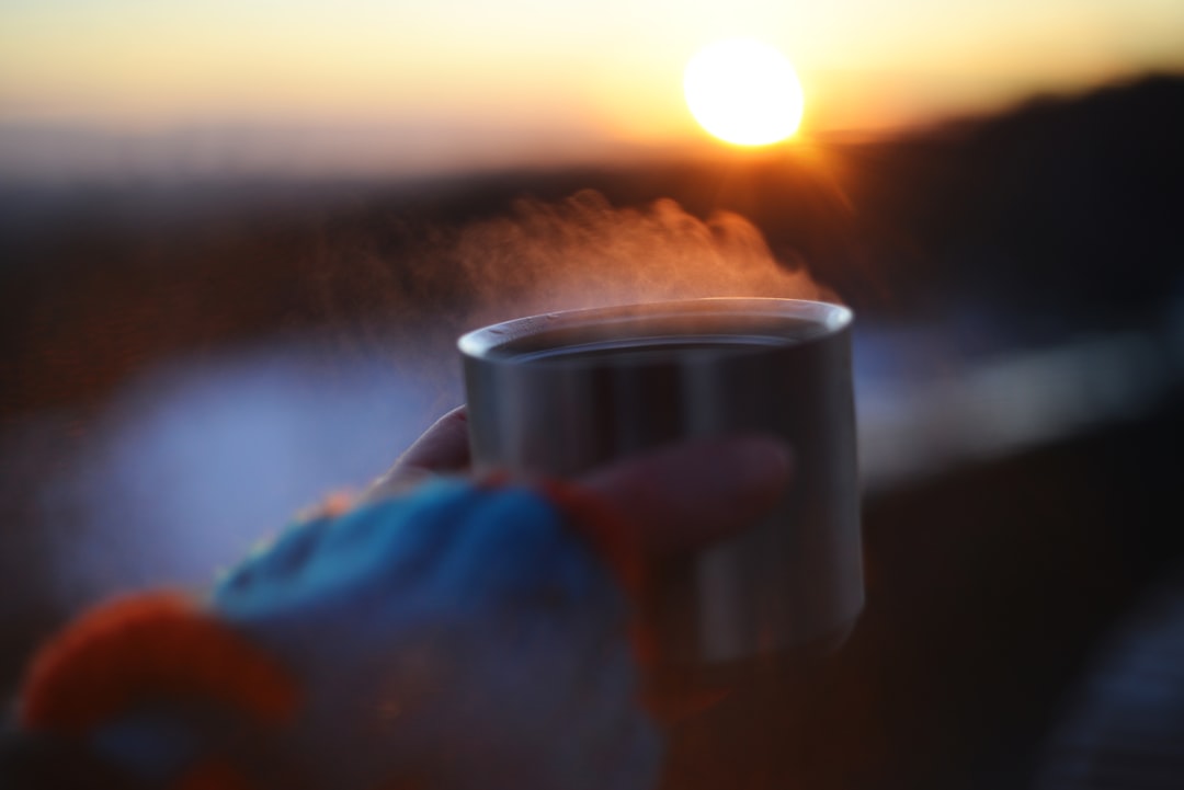 夕暮れの海辺で温かい飲み物を持つ手｜海上がりの体温回復