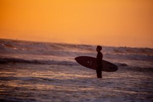 秋の夕暮れの海とサーファー|秋サーフィンの寒さ対策