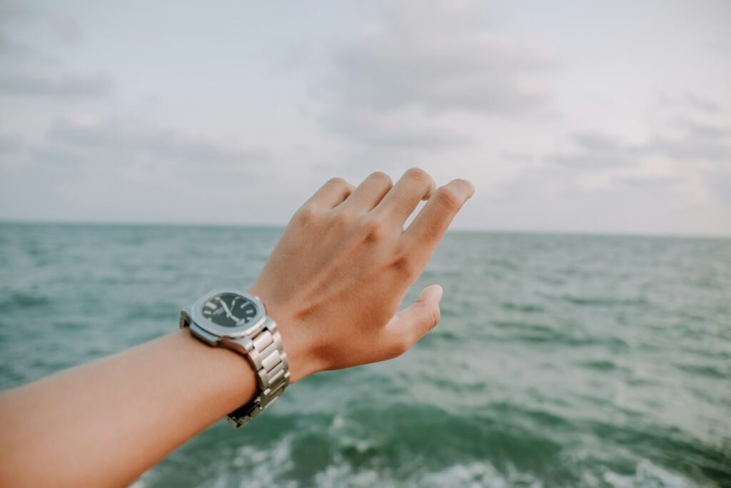 海を背景に手首のスマートウォッチを確認するサーファー｜Apple Watchをサーフィンで使う