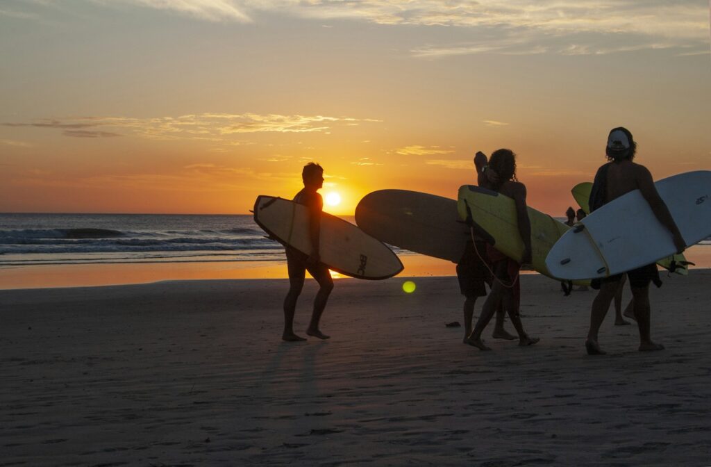 秋の夕暮れの海へ向かうサーファー。9月からは水温の下がり方に合わせたウェットスーツ選びが必要になる