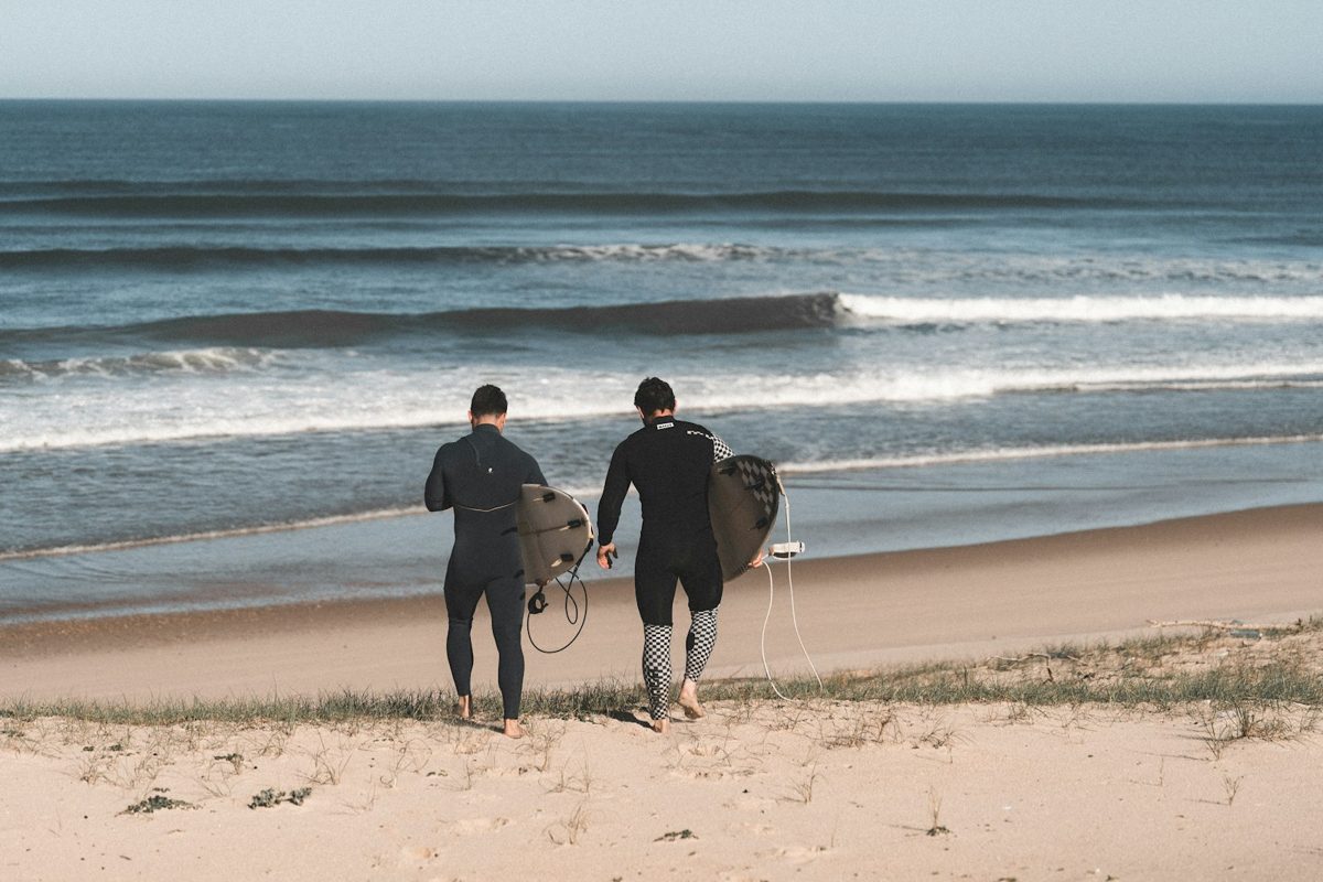 秋のウェットスーツで海へ向かう2人のサーファー