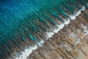 沖縄のリーフに北うねりが割れる様子を空撮で捉えた海岸線