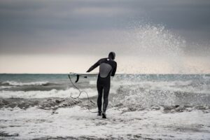 冬の海にセミドライを着て入っていくサーファー