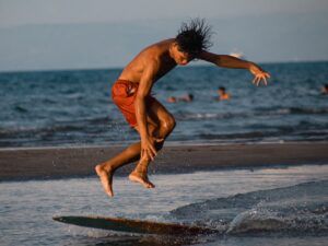 波打ち際でスキムボードに飛び乗る瞬間