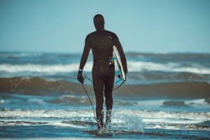 水温が下がり始めた海へ入っていくウェットスーツ姿のサーファー