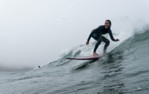 冬の海でウェットスーツを着てサーフィンする様子｜サーフグローブはいつから必要か