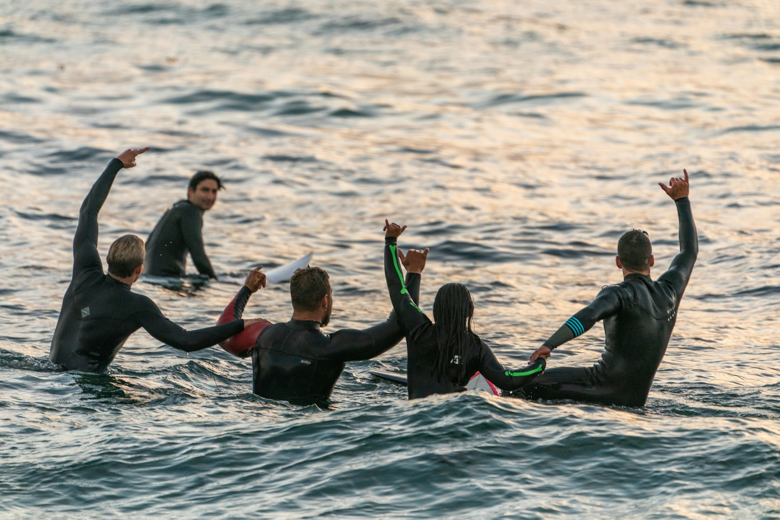 黒いウェットスーツで海に浮かぶサーファーたち。グローブはパドルの感覚を変える