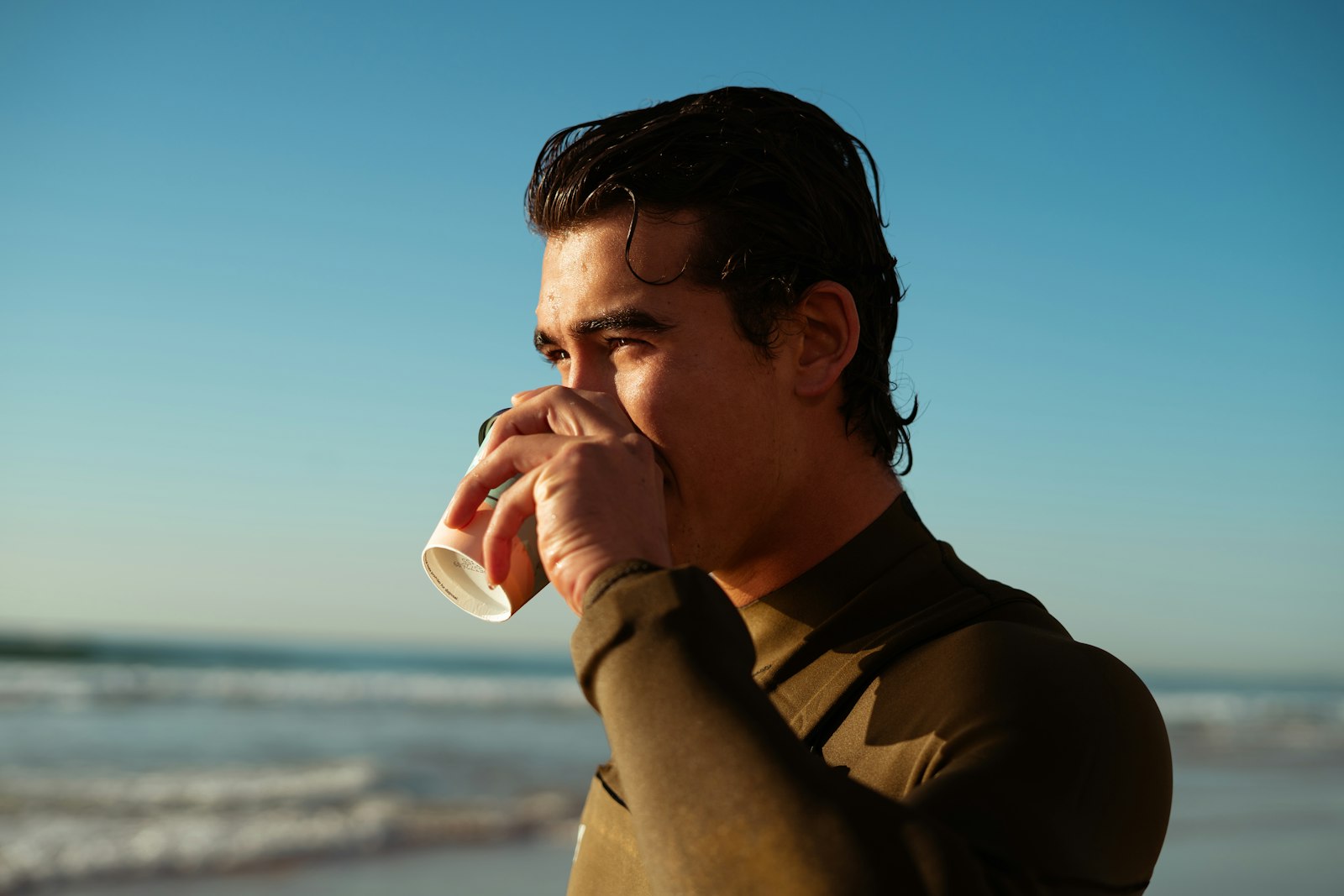 海上がりに浜で温かい飲み物を飲むサーファー｜上がった後の手足の温め方