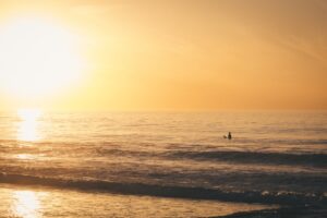 夕暮れの海に立つサーファーのシルエット