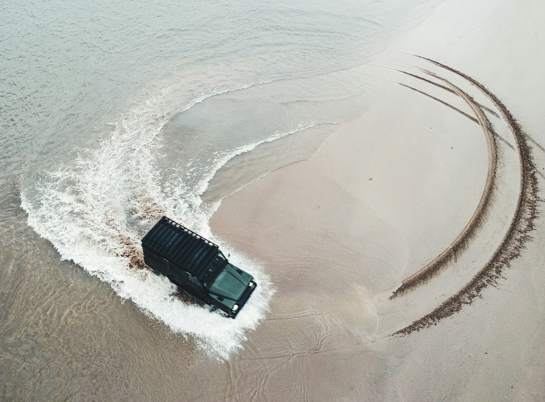 砂浜で車輪を空転させながら走る四輪駆動車