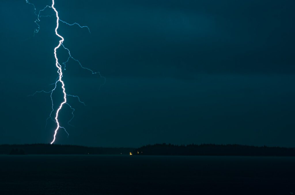 海の上空に走る稲妻。サーフィン中の雷は命に関わる危険