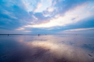 干潮で広がった濡れた砂浜に空が映る夕方のビーチ｜タイドグラフの読み方