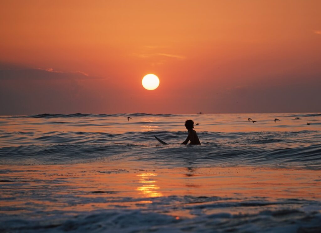 夕日を背に波待ちするサーファーのシルエット